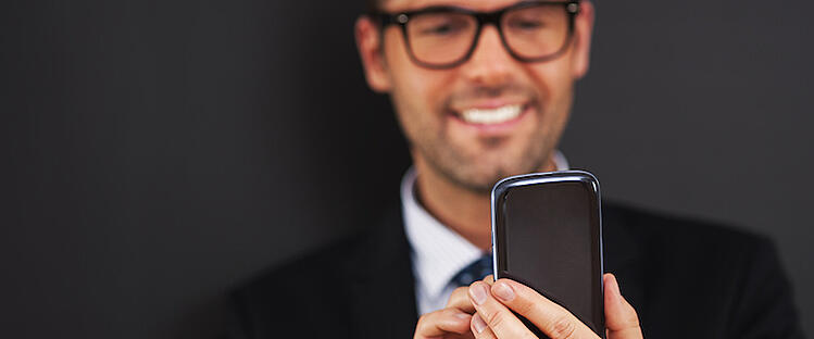 Man looking at his phone and smiling at his improved lead generation results